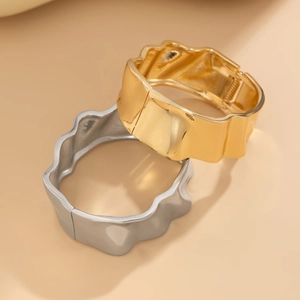 Detail of wavy gold and silver spring hinges bracelets with irregular metallic edges