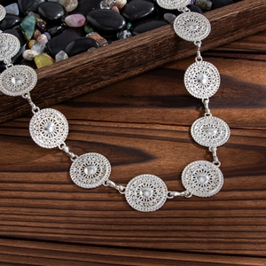 Detailed macro view of silver ethnic filigree metal buckle elements on a wooden surface