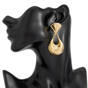 Detail view of golden geometric liquid earrings on black mannequin with high polish finish