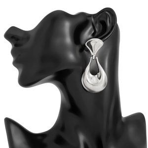 Macro detail of large silver geometric hollow earrings shown on a fashion model bust