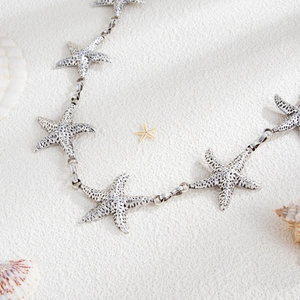 Detail of vintage silver starfish body chain with textured nautical elements for beach wear