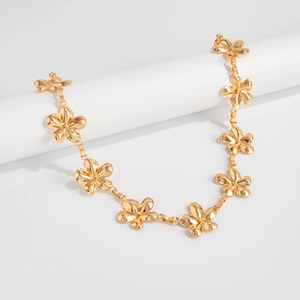 Detailed macro view of golden metal flower body chain with polished mirror finish