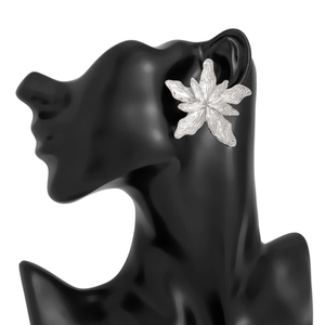 Detail of silver liquid metal flower earrings with hammered texture on black silhouette
