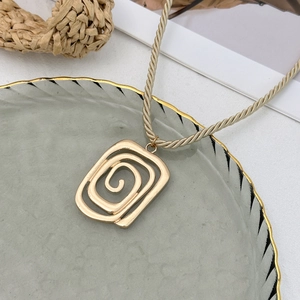 Detail of gold spiral geometric pendant on champagne woven rope necklace with relief texture