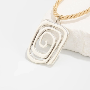 Macro detail of irregular silver spiral pendant on a thick gold-toned twisted cord