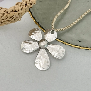 Detail der silbernen strukturierten Blumenkette mit beigem gedrehtem Seilband