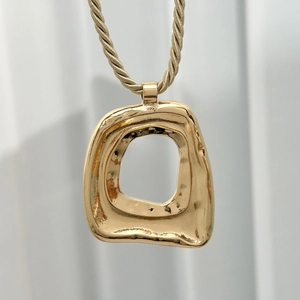 Detail der goldenen Muschel-Halskette mit unregelmäßigem Design und gewebter Kordel