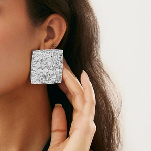 Close-up of large silver square earrings with liquid metal texture and wrinkled finish
