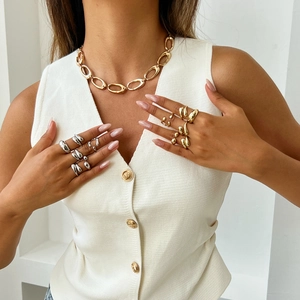 Close-up of gold chunky chain necklace and irregular liquid metal rings on model