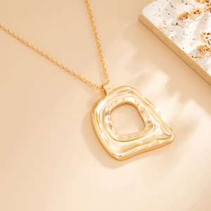 Detailed macro of gold irregular hollow pendant necklace with natural wavy metal texture
