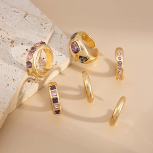 Macro shot of 6-piece gold alloy ring set with purple and pink crystals on travertine stone