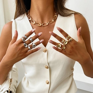Close-up of gold chain necklace and irregular liquid metal rings on female model