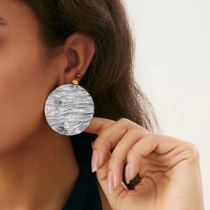 Macro detail of large silver textured U-shaped earrings on model with irregular knot design