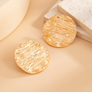 Detailed close-up of golden round earrings with creative liquid lava wrinkled texture
