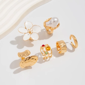 Detailed macro view of gold-toned ring set with baroque pearl and floral liquid lava design