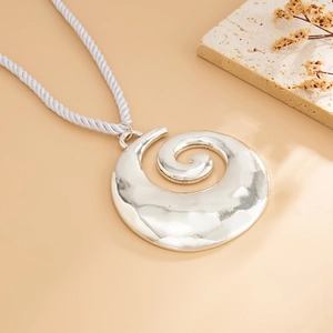Macro detail of silver spiral shell pendant with hammered metal texture on white cord