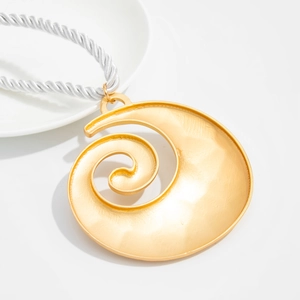 Macro shot of large golden spiral shell pendant on a thick white woven rope necklace