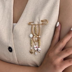 Floral ceramic bead brooch with golden heart pendant on beige linen garment