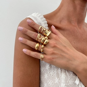 Close-up of stacked gold-plated alloy rings with organic and geometric minimalist designs