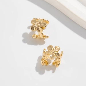 Detailaufnahme goldener Ohrmanschetten in Blumenform mit strukturierten Metallblüten