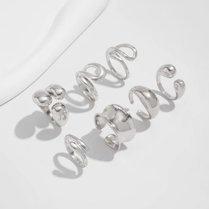Detailed view of seven minimalist silver rings with polished finishes and organic shapes