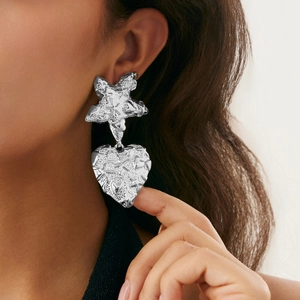 Detail of silver liquid lava metal heart and star earrings on model with hammered texture