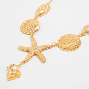 Dettaglio della collana con stella marina dorata con perle delicate e cristalli