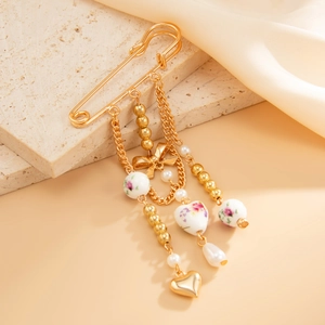 Detailed view of vintage gold safety pin brooch with floral ceramic beads and heart charms
