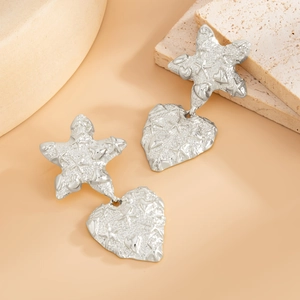 Detailed close-up of silver earrings with embossed star and heart charms on stone base