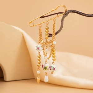 Retro gold bow brooch with heart pendant, ceramic beads and pearls on silk background