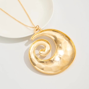 Macro detail of golden snail shell pendant with hammered texture on a long chain