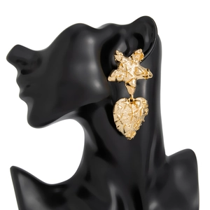 Detailed view of gold starfish and textured lava heart earrings on a black display stand