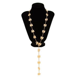 Dettaglio di una lunga collana dorata a fiocco con design a Y e frange su un manichino nero