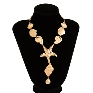 Collana con ciondolo a forma di stella marina e conchiglia dorata su manichino in velluto