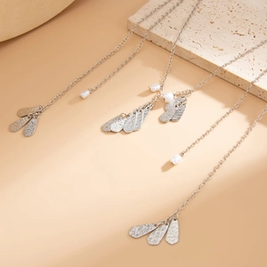 Dettaglio di collane con fiocco d'argento con petali martellati e perle