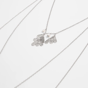Dettaglio collana multistrato argento con ciondoli a foglia martellata e perle bianche