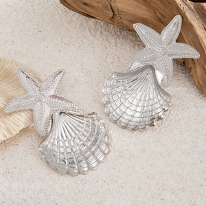 Dettagli di stelle marine e conchiglie argentate su sabbia con corallo e legno naturale
