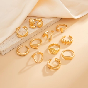 Detail view of eleven assorted golden rings with textures on textured stone and soft fabric
