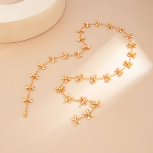 Dettaglio della collana lunga dorata con fiocchi metallici e chiusura a moschettone