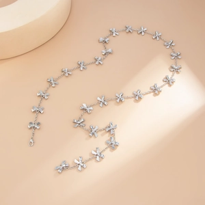 Collana a catena con fiocco argentato e chiusura a moschettone su sfondo beige