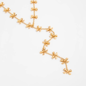 Dettaglio ravvicinato della collana dorata con fiocchi e trama metallica lucida