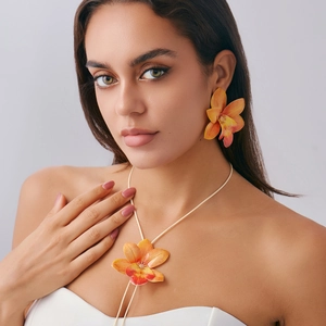 Detailed view of realistic orange orchid necklace and earring set with fabric texture