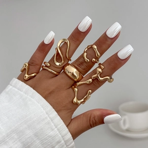 Detail of stacked irregular liquid lava gold metal rings on a model's hand