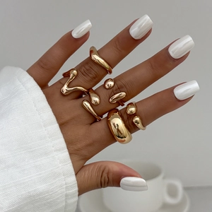 Close-up of minimalist gold-plated teardrop and irregular geometric rings on hand
