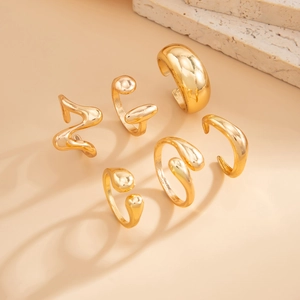 Detailed view of six gold-plated organic rings with a mirror finish and minimalist curves
