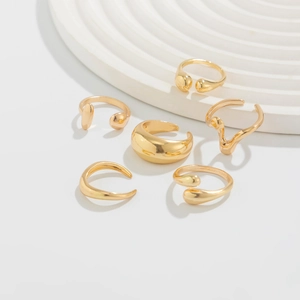Detailed view of 6-piece minimalist gold water drop rings on a white tiered display stand