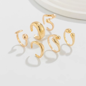 Set of six minimalist golden adjustable rings and ear cuffs with fluid geometric shapes