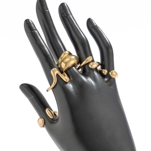 Detailed view of irregular golden geometric drip rings on a black mannequin hand display