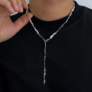Dettaglio della collana a Y in argento con texture metallica fluida e pendente lungo