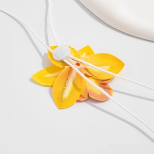 Macro detail of the yellow flower accessory showing the back structure and white elastic cord
